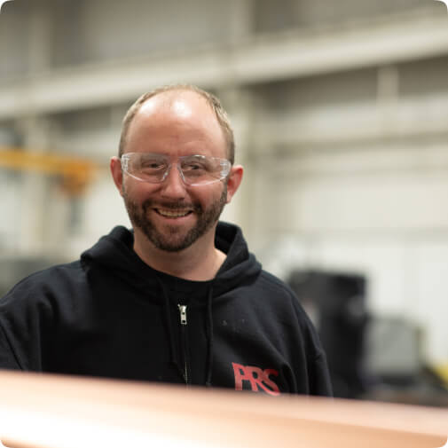 PRS employee wearing safety glasses smiling at camera