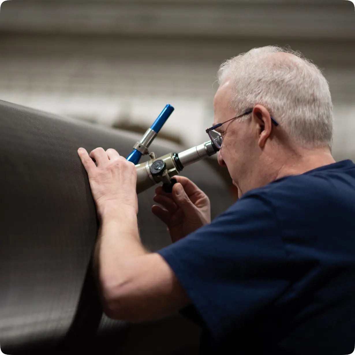 Man with a portable microscope inspecting the surface of a roller.